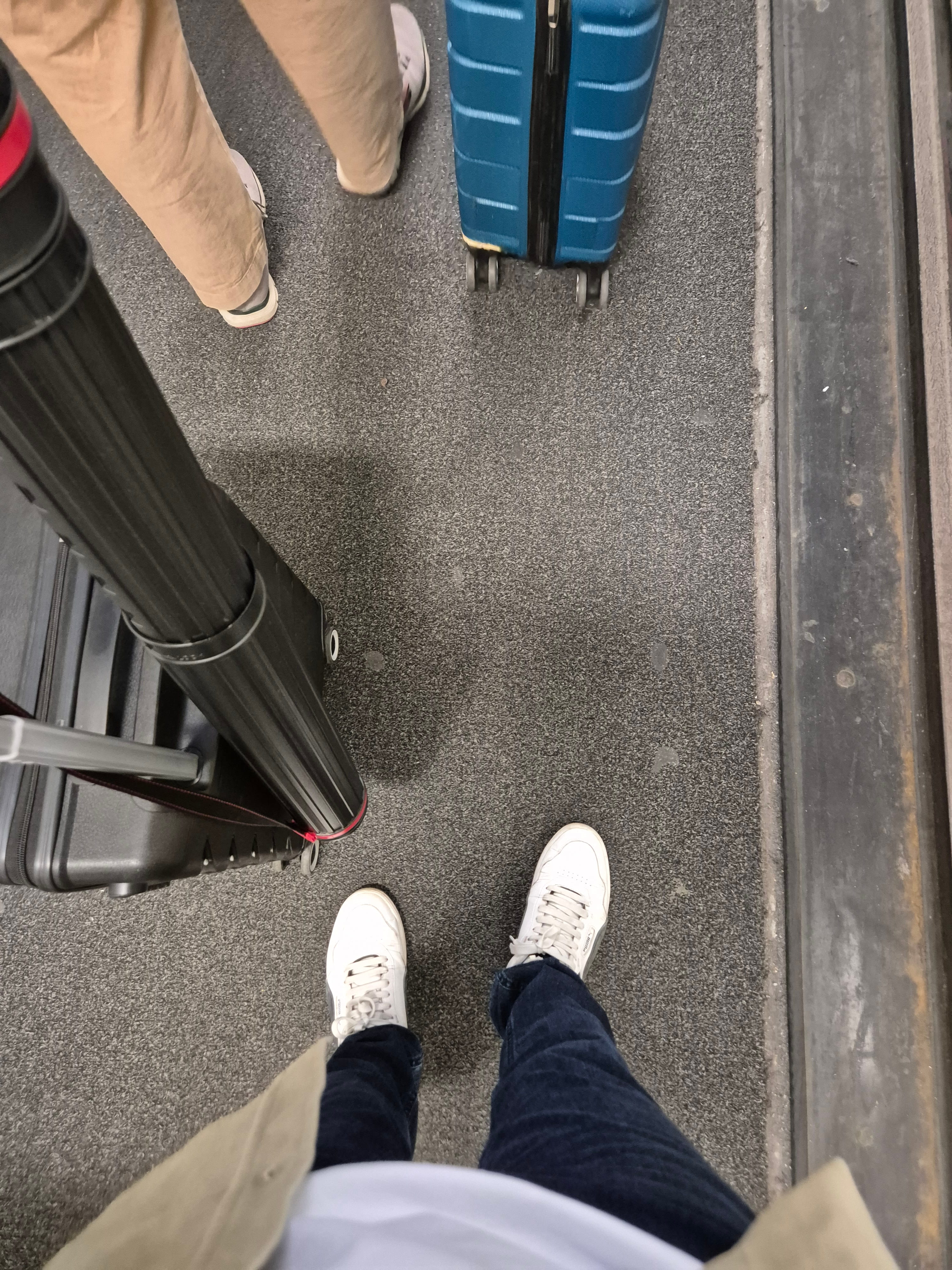 Travel luggage and feet at airport or station, poster tube on suitcase
